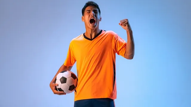 Motivated footballer wearing uniform and holding a ball