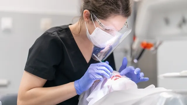 dentista examina la boca y los dientes de un paciente utilizando un explorador dental