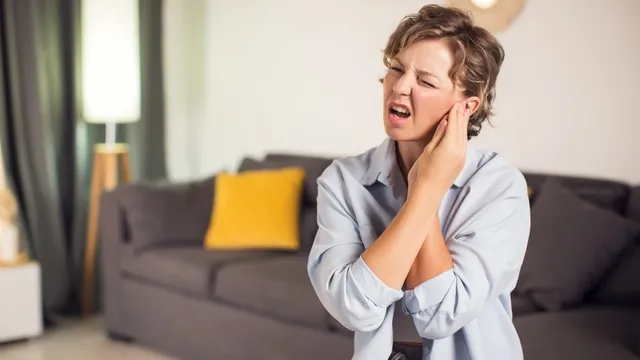 mujer que sufre un dolor agudo en el oído