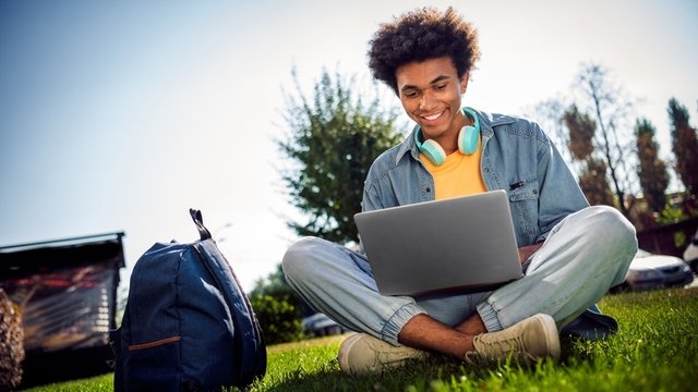 estudiante de buen humor usando su ordenador portátil al aire libre