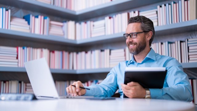 docente trabaja sonriente en la sala de profesores de un colegio o instituto