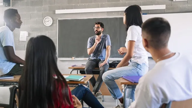 estudiantes adolescentes escuchando y hablando con un profesor joven