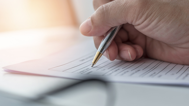 una mano sostiene un bolígrafo para firmar un documento