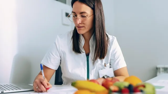 mujer trabaja con un ordenador portátil mientras toma notas en una consulta de nutrición