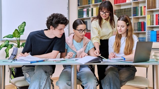 grupo de estudiantes adolescentes con profesora estudian en una biblioteca