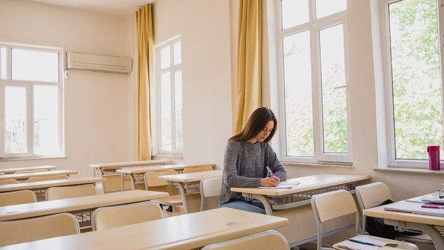 una chica sola en un aula haciendo un examen