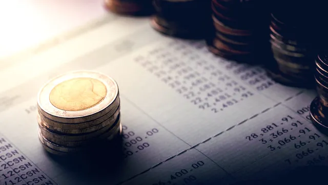 pila de monedas encima de un libro de cuentas