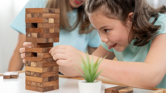 ni&ntilde;a concentrada con un juego de construcciones de madera