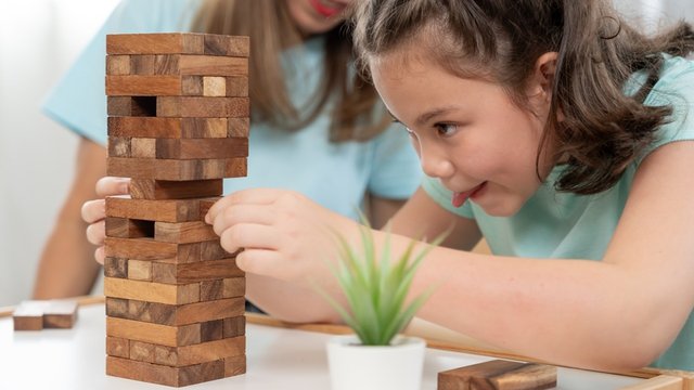 niña concentrada con un juego de construcciones de madera