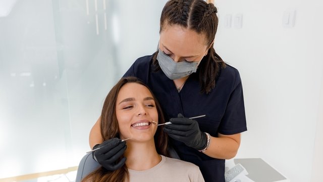 higienista bucodental practicando una limpieza dental a una paciente