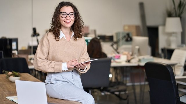 gestora comercial apoyada en una mesa, mientras sostiene una tablet