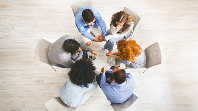 grupo de personas sentadas en círculo durante una sesión de terapia