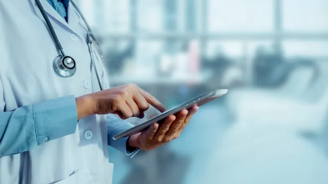 persona lleva puesto un uniforme sanitario y utiliza una tableta