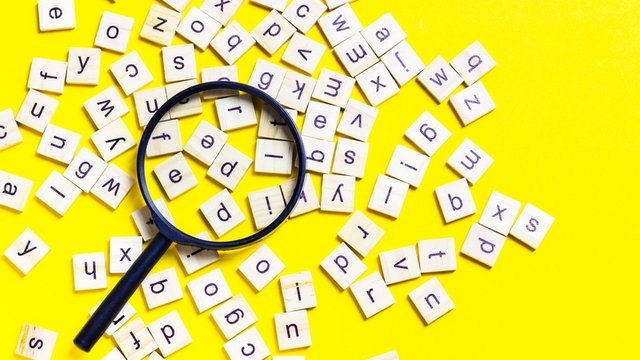 alfabeto compuesto por baldosas cuadradas de madera esparcido sobre un fondo de color amarillo