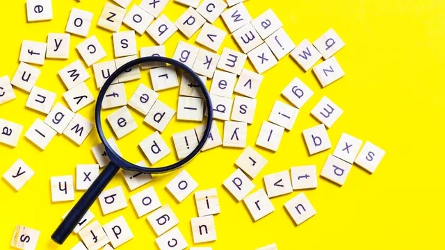 alfabeto compuesto por baldosas cuadradas de madera esparcido sobre un fondo de color amarillo