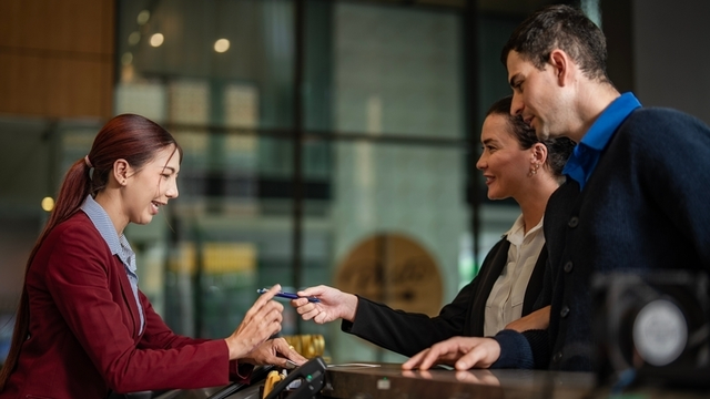 guest experience manager ayudando a unos hu&eacute;spedes que acaban de llegar a la recepci&oacute;n del hotel