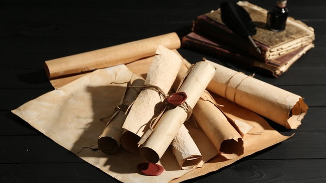 Muchos viejos rollos y libros en la mesa de madera negra, en primer plano