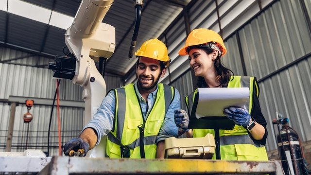 ingenieros industriales trabajando en una fábrica con robots inteligentes