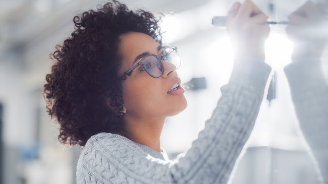 mujer joven escribiendo en una pizarra blanca