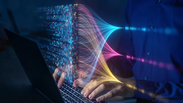 proyección en varios colores de 1 y 0 mientras una persona usa el teclado de un ordenador portátil
