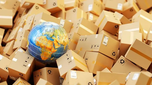 A small glass globe showing Europe and Africa sits atop a massive pile of cardboard shipping boxes, representing global commerce and international shipping logistics.
