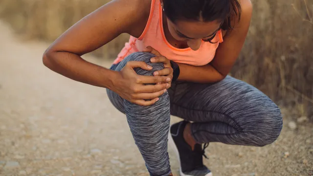 deportista agachada con dolor en la pierna