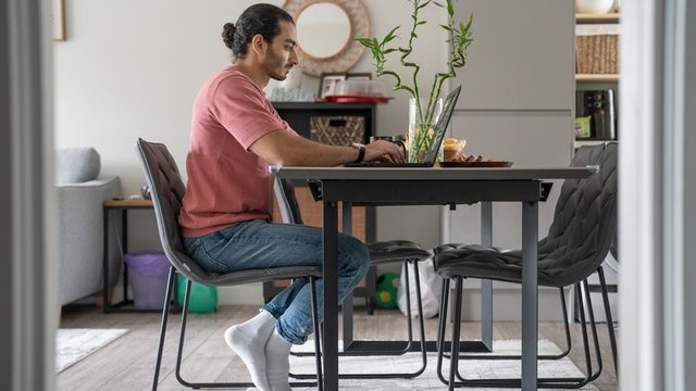 hombre trabajando con un ordenador portátil en el salón de una casa