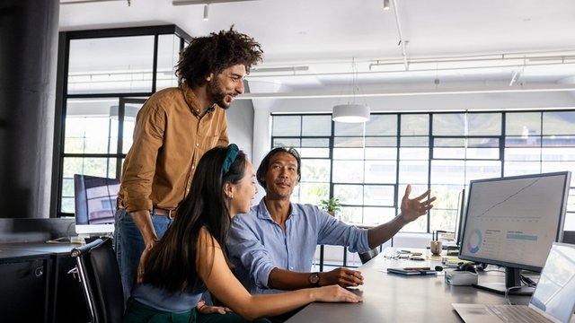 Equipo de negocios analiza datos frente a un ordenador y debate sobre la estrategia