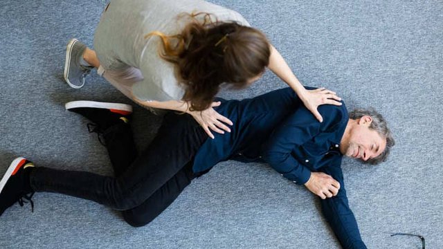 persona en el suelo con una lipotimia siendo atendida