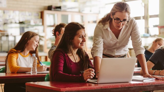 profesora atendiendo las dudas de una alumna en clase