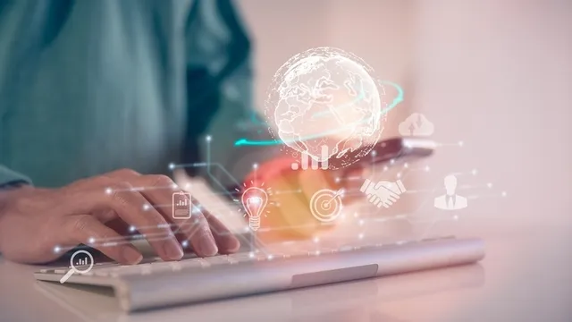 persona usando a la vez el teclado de un ordenador y un teléfono móvil