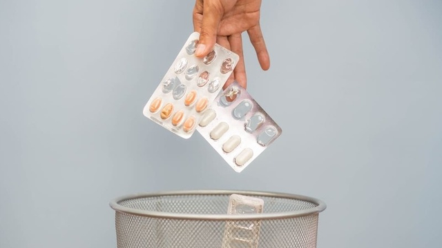 Imagen de una mano tirando a la basura medicamentos caducados