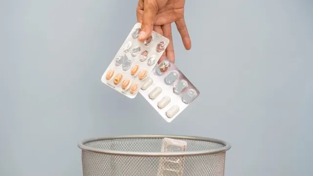 Imagen de una mano tirando a la basura medicamentos caducados