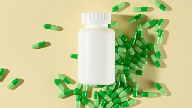 imagen de un bote con pastillas de color verde