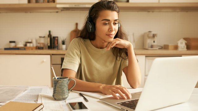 chica trabaja la traducción de un texto en la cocina con un ordenador portátil
