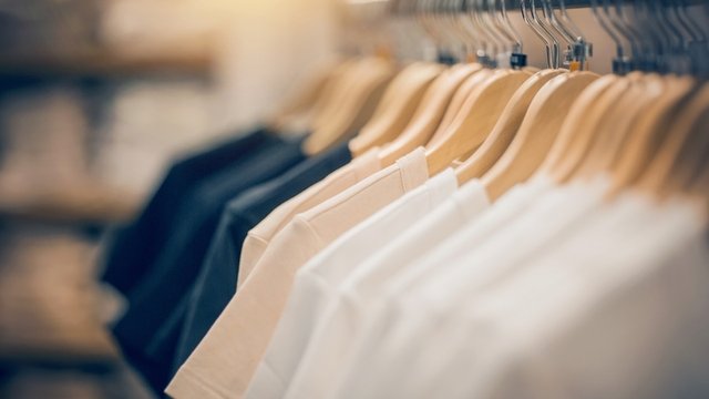 camisetas de varios colores colgadas en perchas de manera ordenada