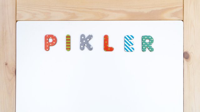 texto “PIKLER” escrito sobre una pizarra blanca