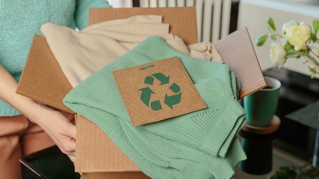 persona cogiendo caja con ropa de segunda mano o reciclada