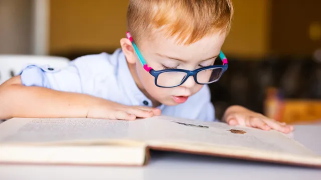 niño con gafas aprende a leer un libro