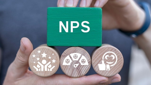 hombre sostiene bloques con el texto &ldquo;NPS&rdquo; e iconos relacionados con la satisfacci&oacute;n del cliente