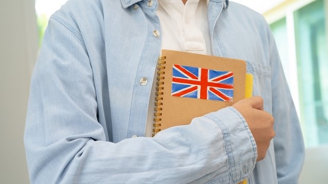 estudiante sostiene una libreta con la bandera británica dibujada en la portada