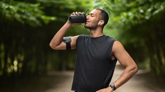 deportista tomando un batido de proteínas tras hacer una carrera por el parque