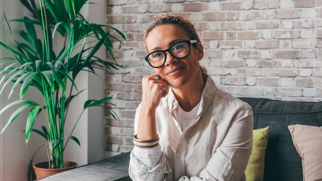 mujer de mediana edad, sentada en un sofá y posando para una foto