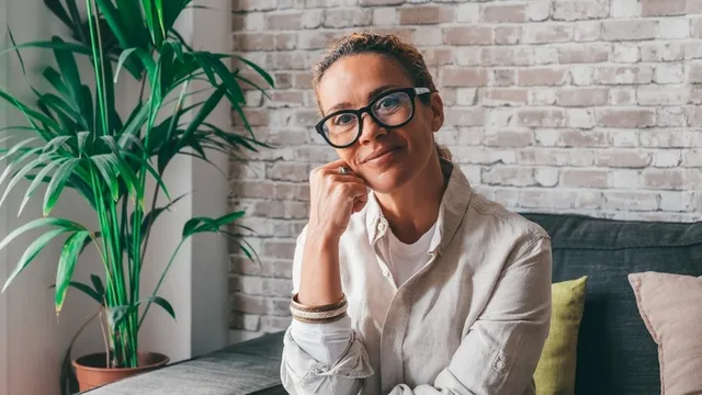 mujer de mediana edad, sentada en un sofá y posando para una foto