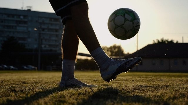 pies de futbolista pateando una pelota en un campo de fútbol