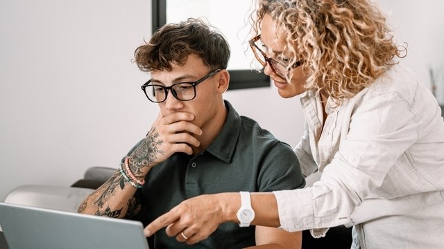 una profesora ayuda a un alumno a resolver sus dudas sobre un ejercicio