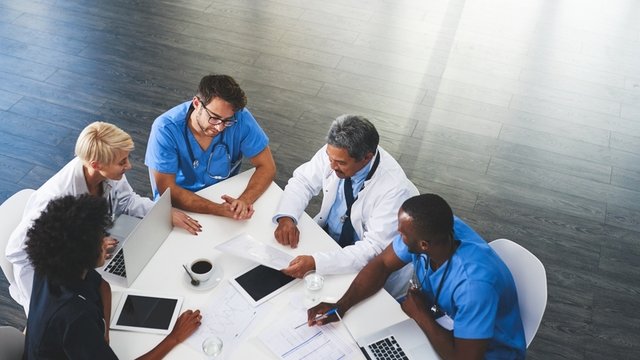 equipo de profesionales de la salud hablando sentados alrededor de una mesa