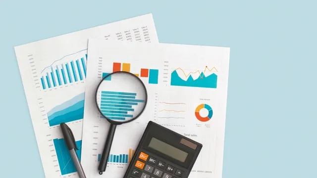documentos financieros, calculadora, lupa y bolígrafo sobre una mesa de color azul claro