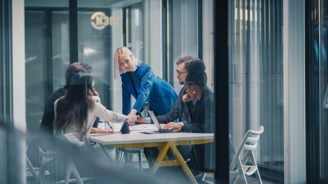 una directora dirige una reunión de negocios en una oficina de cristal