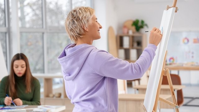 profesora de Dibujo pinta sobre un lienzo en el aula de un colegio o instituto